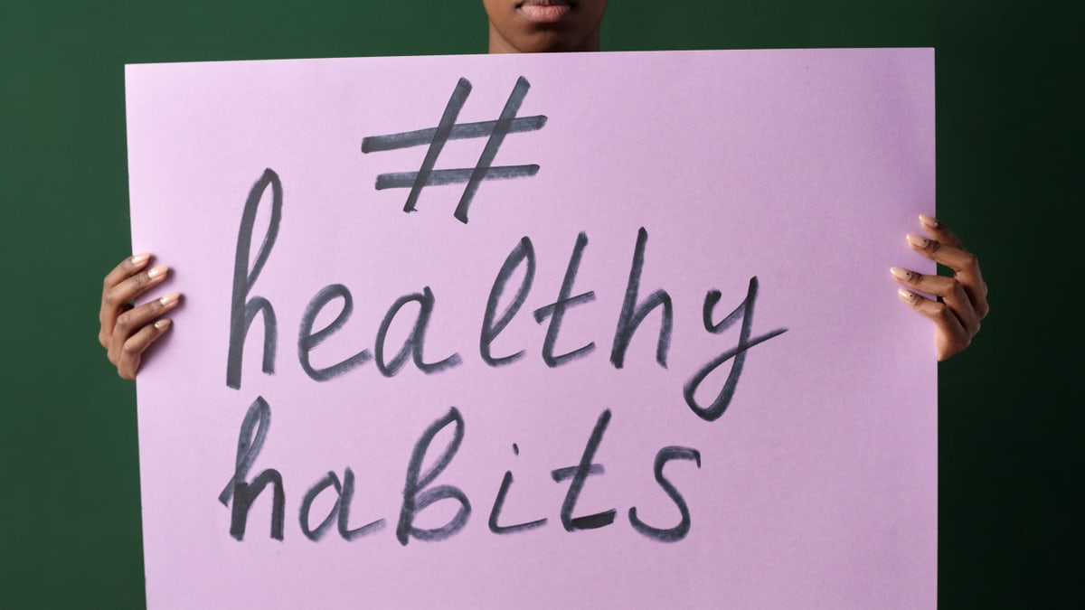 Person holding a "#healthyhabits" sign, emphasizing wellness.